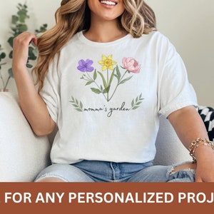 Puede incluir: Camiseta blanca con un dise&ntilde;o floral y el texto "momma's garden".