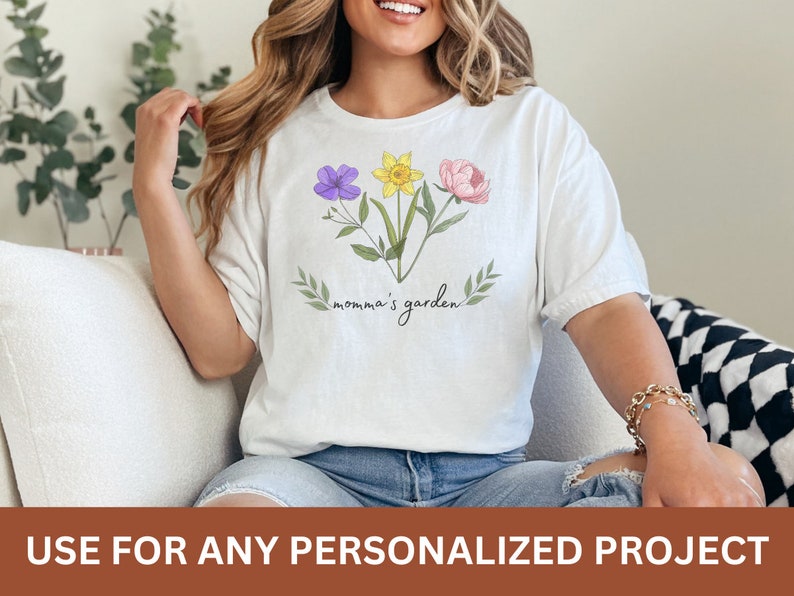 Puede incluir: Camiseta blanca con un dise&ntilde;o floral y el texto "momma's garden".