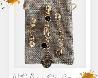 May include: A set of three gold hair coils with black beads and shell charms, displayed in a brown burlap pouch. The pouch has a drawstring closure and the coils are arranged in a row. The coils are made of wire and have a spiral shape. The charms are attached to the coils with a small loop. The pouch has the text "NotSoBazaar.Etsy.Com" printed on the bottom.