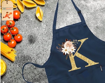 May include: Navy blue kitchen apron with a large gold glitter letter K and floral design. The letter K is surrounded by white and pink flowers.