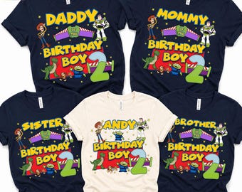 May include: A collection of five navy blue and one cream t-shirt featuring Toy Story characters including Woody, Buzz Lightyear, Rex, and an alien. Each shirt displays the text Birthday Boy, a large number 2, and specific family titles.
