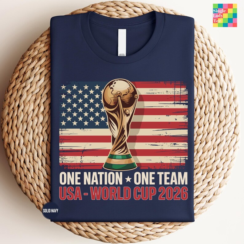 A navy blue t-shirt with a graphic design featuring the FIFA World Cup trophy and the text "One Nation, One Team USA-World Cup 2026" printed on it.
