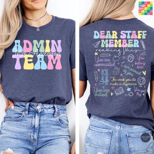 May include: A navy blue t-shirt featuring the text ADMIN TEAM and Mrs Anderson on the front. The back displays the text DEAR STAFF MEMBER reading this... You are appreciated, You belong here, You are respected, I am proud of you, The work you do make a difference, You are valued, You got this, alongside various school supply icons.