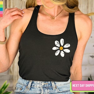 a woman wearing a black tank top with a flower on it