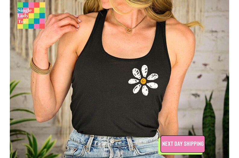 a woman wearing a black tank top with a flower on it