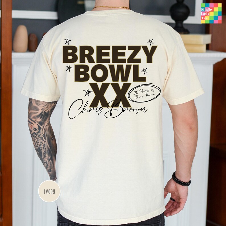 a person wearing a white t-shirt with a graphic design featuring the text "BREEEZY BOWL XX" and the name "Chris Brown" along with a small text that says "20 Years of Chris Brown".