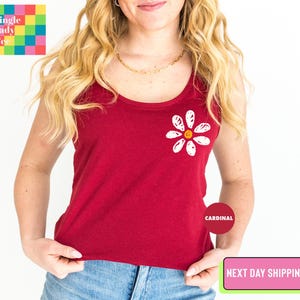 a woman wearing a red tank top with a flower on it