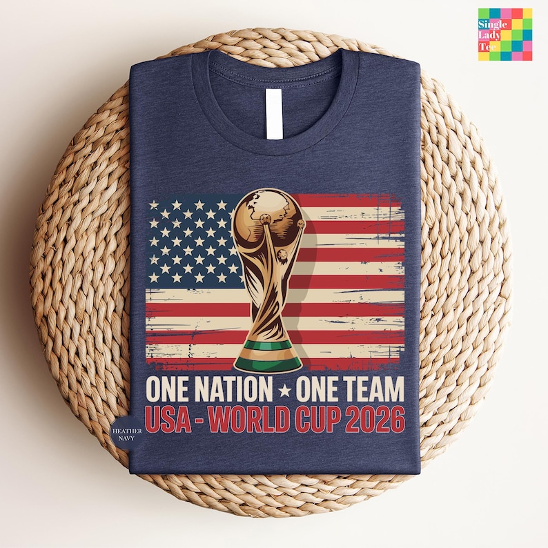 A navy blue t-shirt with a graphic design featuring the FIFA World Cup trophy and the text "One Nation, One Team USA-World Cup 2026" printed on it.