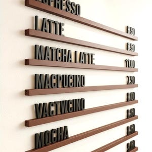 Op de afbeelding: Een menubord van een koffiehuis met bruine planken en zwarte letters. Het menu omvat espresso, latte, matcha latte, macpucino en mokka. Het bord is op een witte muur gemonteerd.