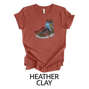 May include: A heather clay t-shirt with a graphic of a hiking boot with the word "EXPLORE" printed on it.