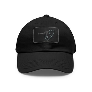 May include: Black cotton baseball cap with a black patch featuring the text "namaste" and a stylized heart design.