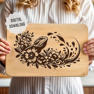May include: A brown wooden chopping board with a black and white design of a bearded dragon lizard with floral accents.