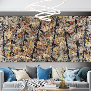 Puede incluir: Pintura abstracta con un diseño caótico y colorido con salpicaduras de pintura negra, blanca, amarilla, azul y roja. La pintura está enmarcada y colgada en una pared gris sobre un sofá gris.