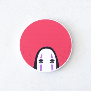 Puede incluir: Un bot&oacute;n redondo blanco con un fondo rosa y una cara estilizada de la pel&iacute;cula de animaci&oacute;n El Viaje de Chihiro. La cara tiene una base blanca con ojos negros y l&iacute;neas verticales moradas.