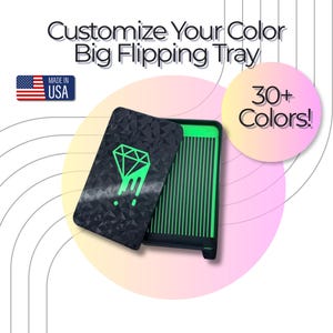 Puede incluir: Una bandeja para pintura de diamantes negra con un patrón geométrico y un logotipo de diamante verde. La bandeja presenta un interior ranurado verde e incluye el texto Customize Your Color Big Flipping Tray, 30+ Colors!, y Made in USA.