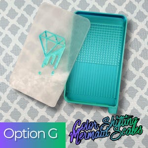 May include: A rectangular teal tray with a grid-patterned base and a matching translucent white lid featuring a raised teal diamond graphic. The lid has a subtle geometric texture, and the tray includes a small pouring spout at one corner.