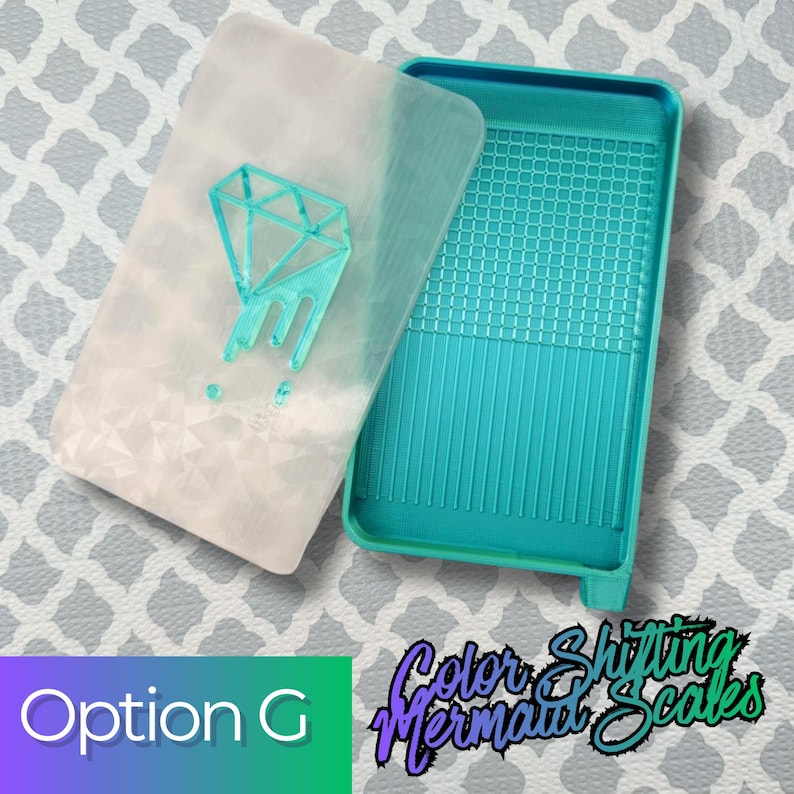 May include: A rectangular teal tray with a grid-patterned base and a matching translucent white lid featuring a raised teal diamond graphic. The lid has a subtle geometric texture, and the tray includes a small pouring spout at one corner.