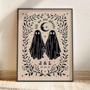 Puede incluir: Impresión artística enmarcada en negro con dos figuras de fantasmas tomados de la mano, con el texto "till we are ghosts" encima. La impresión incluye una luna creciente y una estrella, rodeadas por un diseño floral, y las iniciales "J & L" con la fecha "10.10.25".