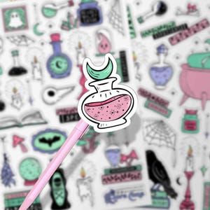 This is a close up shot of one of the potion stickers (a pink sparkly potion with a teal moon lid) on a pink pen.