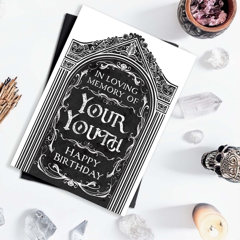 Printable bday card that is 5x7” and vertical. Features an illustrated black gravestone with ornate borders and the words, “in loving memory of your youth. Happy birthday”