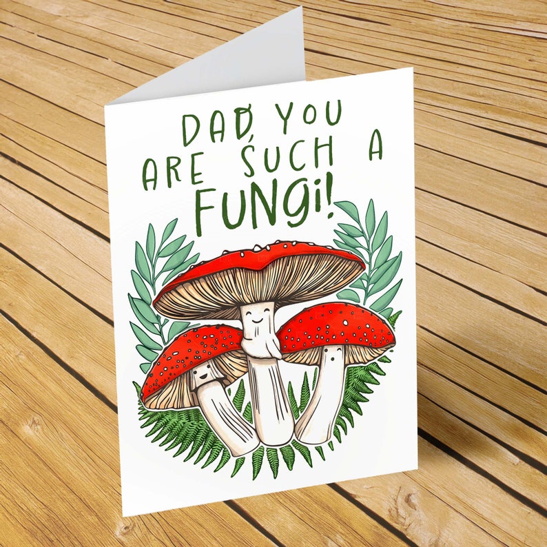 Printable 5x7 card that has 3 hand illustrated toadstool mushrooms with smiling faces and green leaves behind them. The words, "Dad, you are such a fungi!" are above the toadstools.