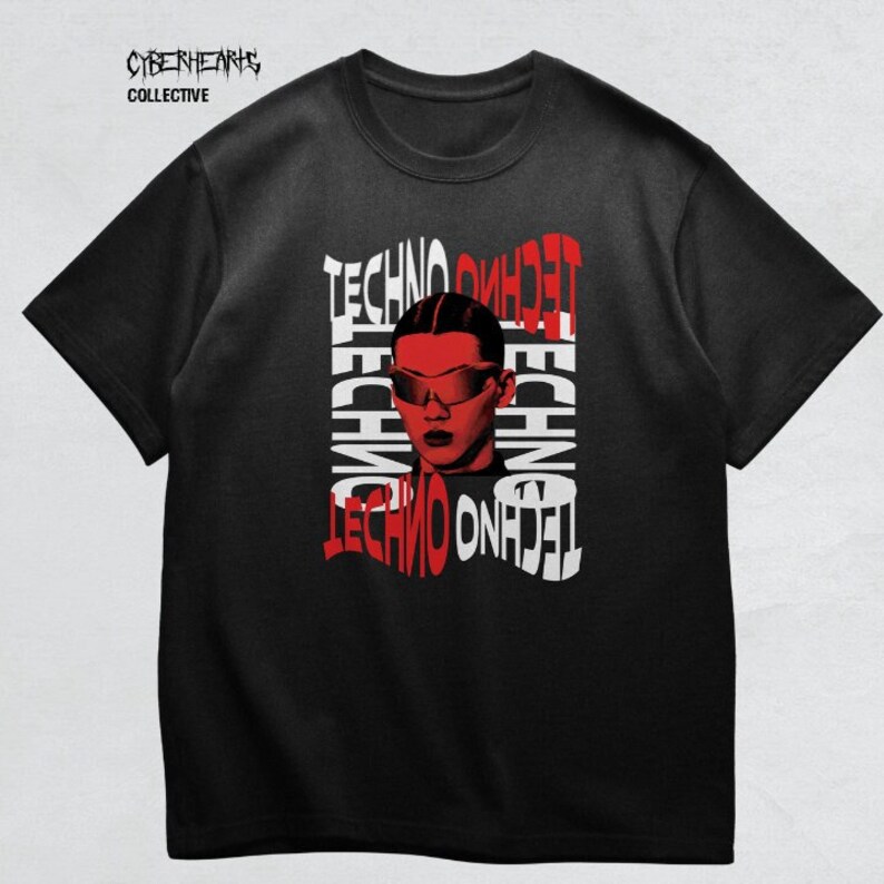 May include: Black t-shirt with a red and white graphic design featuring a person wearing sunglasses and the word "techno" repeated multiple times. The text "Cyberhearts Collective" is printed in white at the top of the shirt.