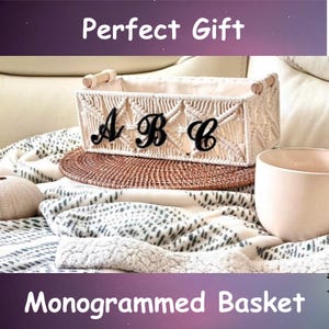 May include: A woven basket with the letters "A B C" on the front. The basket is beige with wooden handles and sits on a round, woven mat. The text "Perfect Gift" and "Monogrammed Basket" are displayed.