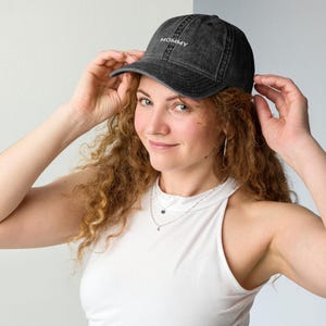 May include: A black, distressed baseball cap with the word "MOMMY" embroidered in white. The cap has a curved peak and a classic six-panel design. The hat is made of a soft, worn material.