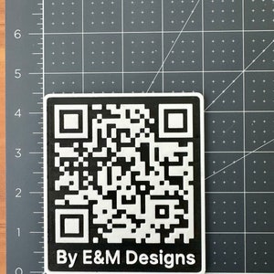 May include: A black and white QR code with the text "By E&M Designs" below it.