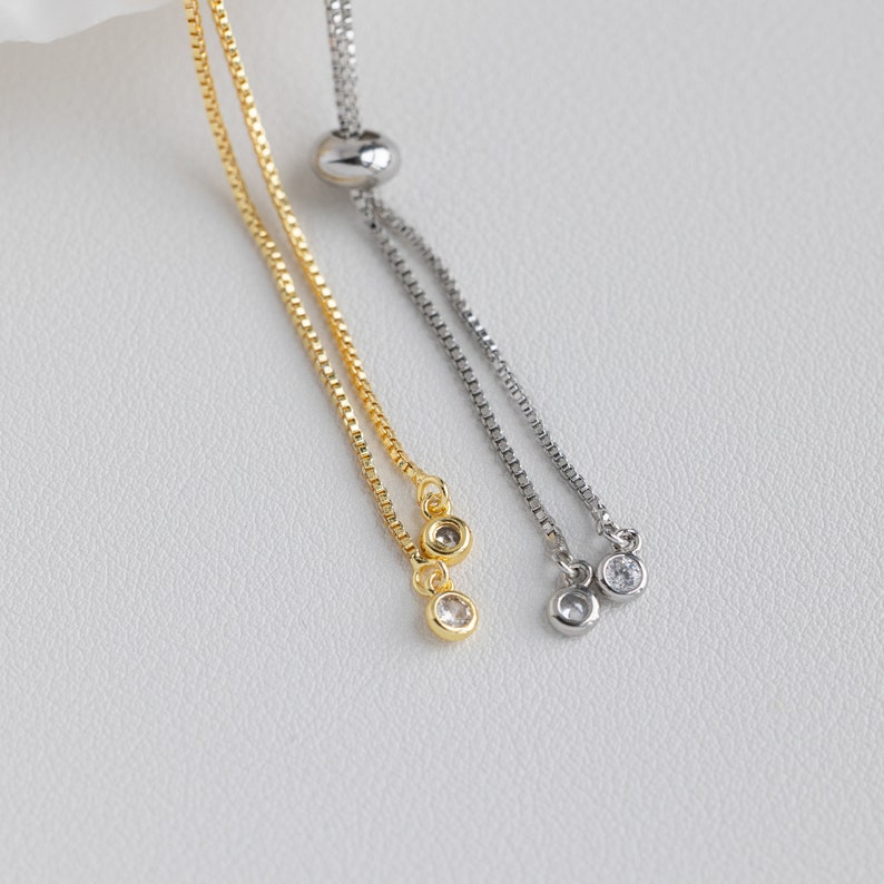 Puede incluir: Dos pulseras ajustables con dise&ntilde;o de cadena. Una pulsera es dorada con una cuenta de cristal transparente en el extremo. La otra pulsera es plateada con una cuenta de cristal transparente en el extremo.