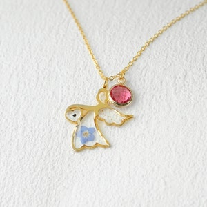 May include: Gold necklace with a delicate angel pendant featuring a blue flower and a pink gemstone.