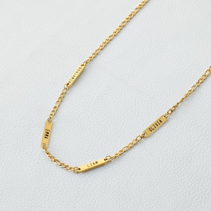 Op de afbeelding: Gouden ketting met vier rechthoekige naamplaatjes. De plaatjes zijn gegraveerd met de namen "Benjamin", "Emma", "Liam" en "Olivia".