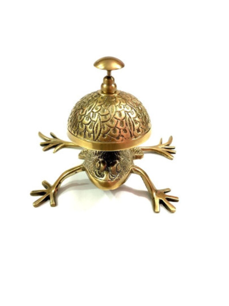 Pode incluir: Um sino de servi&ccedil;o em forma de sapo dourado com uma c&uacute;pula decorativa com padr&otilde;es. O sino &eacute; feito de lat&atilde;o e tem um design tradicional.