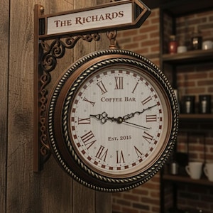 Op de afbeelding: Een dubbelzijdige klok in vintage-stijl met de tekst "Coffee Bar" en "Est. 2015" op de wijzerplaat. De klok heeft Romeinse cijfers en decoratieve wijzers. Het bord erboven luidt "The Richards". De klok is aan een houten muur bevestigd.