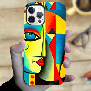 May include: A colorful phone case featuring an abstract face design. The case has a yellow background with blue, red, and orange geometric shapes. The face has a blue eye, red lips, and a yellow nose. The case is designed for a smartphone.