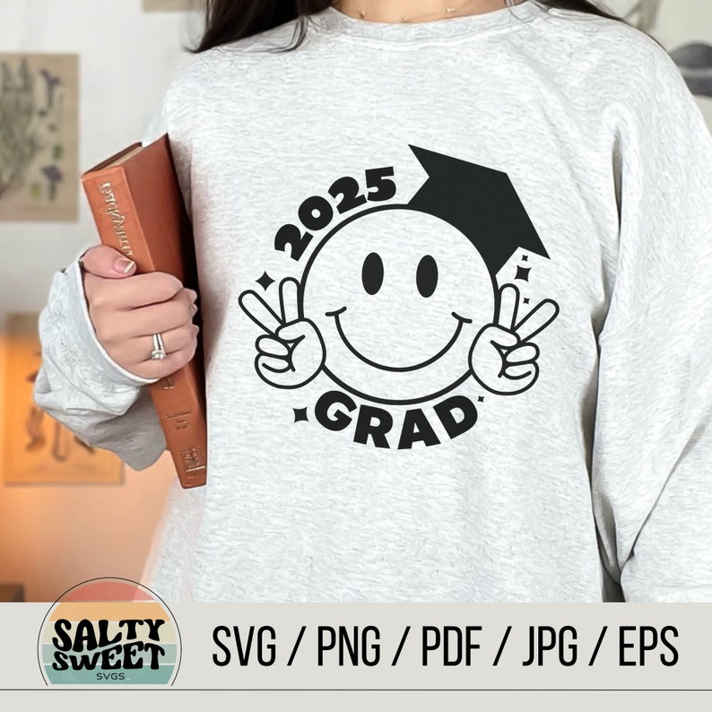 May include: A gray sweatshirt with a black graphic design of a smiley face wearing a graduation cap. The text "2025 GRAD" is around the smiley face.