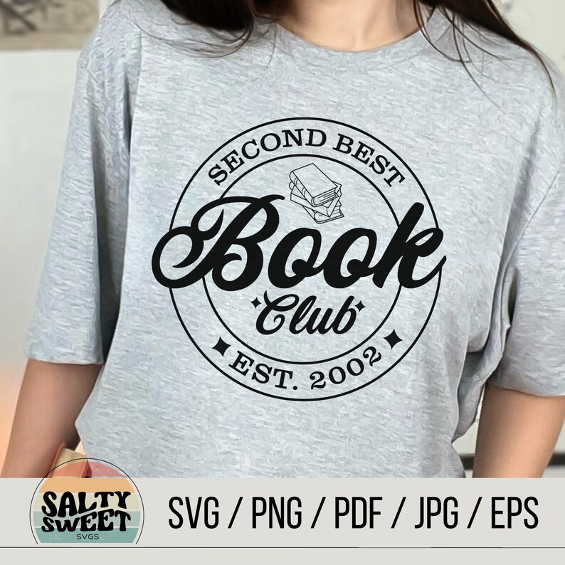K&ouml;nnte beinhalten: Ein graues T-Shirt mit einem schwarzen Kreisdesign, auf dem "Second Best Book Club Est. 2002" steht und sich eine Stapel B&uuml;cher im Kreis befindet.
