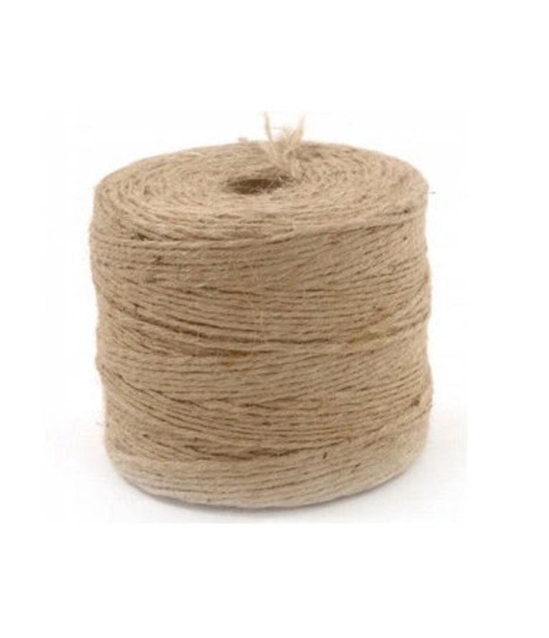 May include: A roll of natural brown twine, made from jute fibers, is wound tightly on a spool. The twine is a natural color and has a rough texture.