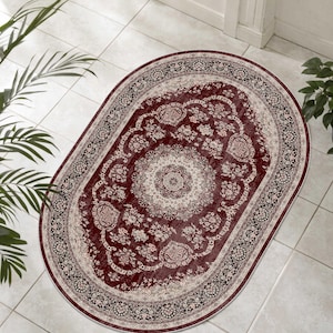 May include: Oval area rug with a traditional floral design. The rug features a deep red center with a cream-colored medallion and floral border. The outer border is black and cream. The rug is placed on a tiled floor.