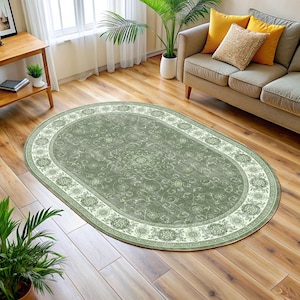 Pode incluir: Um tapete oval com um campo central verde-s&aacute;lvia e uma borda creme. O tapete apresenta um padr&atilde;o floral e de rolagem detalhado. Est&aacute; colocado sobre um piso de madeira em uma sala de estar. Dimens&otilde;es aproximadas: 200 cm x 300 cm.