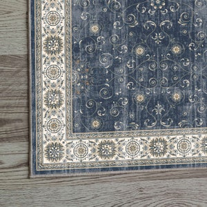 K&ouml;nnte beinhalten: Ein blauer und cremefarbener Teppich mit einem Blumenmuster. Der Teppich hat einen Rand mit einem sich wiederholenden Muster aus Kreisen und Blumen.