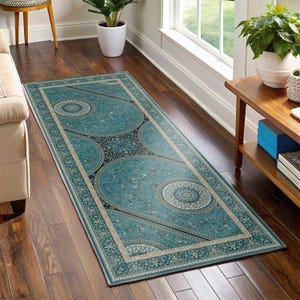 May include: A teal blue runner rug with a black and white geometric pattern. The rug has a cream-colored border with a floral design.