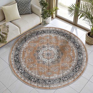 May include: A round area rug with an intricate floral pattern in shades of tan, black, and white. The rug has a distressed, vintage appearance and is placed on a tiled floor. The rug's design features a central medallion and multiple borders.
