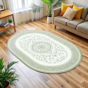 Puede incluir: Una alfombra ovalada verde y blanca con un patrón floral y un medallón central. La alfombra está sobre un suelo de madera en un salón.