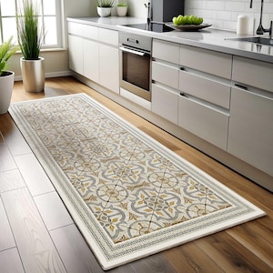 以下が含まれることがあります： 白の縁取りが付いた、ベージュとグレーの模様のキッチンランナーラグ。ラグはモザイクのような幾何学模様のデザインです。