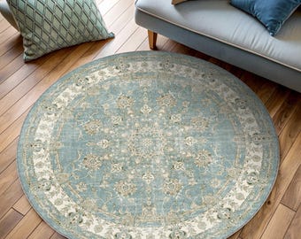 Puede incluir: Una alfombra redonda con una paleta de colores azul claro y crema, que presenta un medallón floral central y patrones botánicos intrincados. El diseño incluye un borde decorativo ancho con motivos florales repetidos.