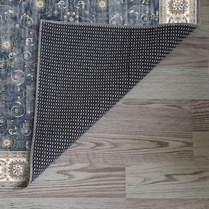 K&ouml;nnte beinhalten: Ein blauer und cremefarbener Teppich mit Muster und rutschfester R&uuml;ckseite. Der Teppich hat ein florales Design mit goldenen Akzenten.