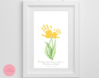 Könnte beinhalten: Gerahmter Druck mit einer gelben Handabdruck-Blume und grünen Blättern. Der Druck enthält den Text "Danke, dass du uns beim Wachsen hilfst" in grüner Schrift. Der Hintergrund ist weiß.