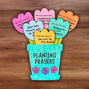 May include: A colorful paper craft depicting a bouquet of flowers in a turquoise pot. Each flower petal has a handwritten prayer. The pot reads "PLANTING PRAYERS" with three pink and purple flowers below.