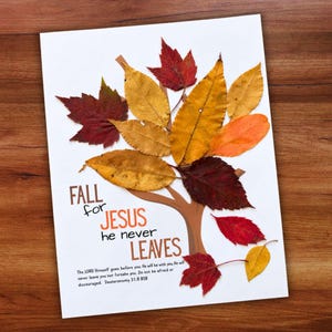 Peut inclure: Une impression blanche avec une illustration d'arbre marron décorée de vraies feuilles d'automne rouges, orange et jaunes. Le texte indique : FALL for JESUS he never LEAVES. The LORD Himself goes before you; He will be with you. He will never leave you nor forsake you. Do not be afraid or discouraged. Deuteronomy 31:8 BSB.
